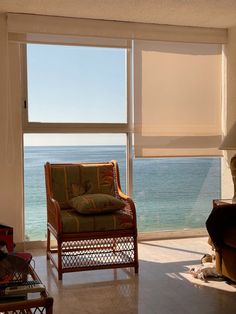 a living room with an ocean view from the couch and chair in front of the window