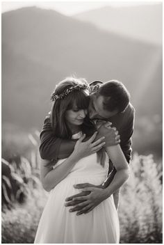 a man and woman embracing each other in black and white photo with mountains in the background