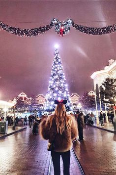 a woman standing in front of a christmas tree