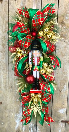 a wreath with a nutcracker on it hanging on a wooden wall in front of a door