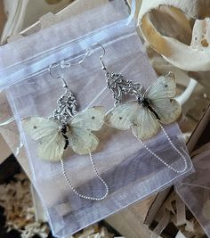 a pair of butterfly earrings sitting on top of a bag