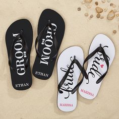 three pairs of personalized flip flops on the sand with shells in the background