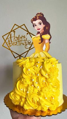 a hand holding up a yellow cake with frosting roses on it and a happy birthday card