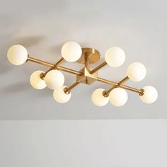 an image of a modern light fixture with white balls on it's face and gold fixtures