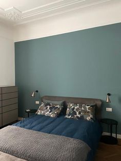 a bedroom with blue walls and grey bedding