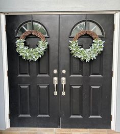 two black double doors with wreaths on them