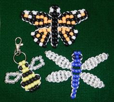 several beaded keychains are arranged on a green surface, including a butterfly and a bee