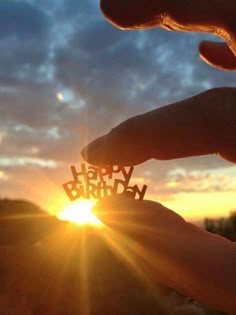 someone is holding out the word happy birthday in front of the sun with their fingers