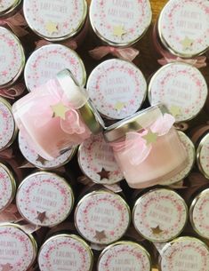 two pink candles sitting on top of each other in front of small round tins