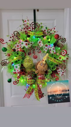 a christmas wreath on the front door decorated with green and red ribbons, lights and a teddy bear