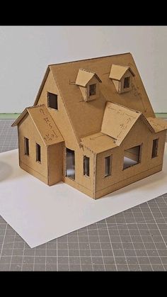 a paper model of a house on top of a piece of white paper next to scissors