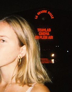 a woman standing in front of a neon sign