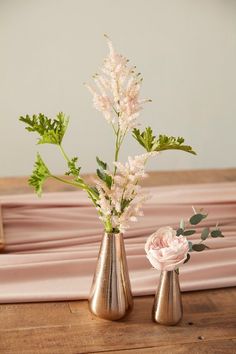 two vases with flowers in them sitting on a table