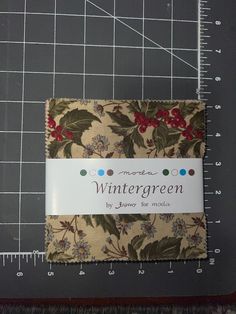 a piece of fabric with holly leaves on it next to a ruler and measuring tape