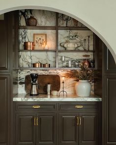 a kitchen with marble counter tops and wooden cabinets in the center is an archway that leads to another room