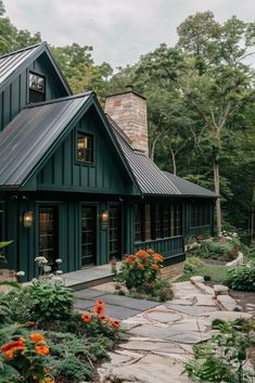 a green house with lots of windows and flowers in the front garden area next to it