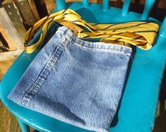 a pair of jeans sitting on top of a blue chair next to a yellow ribbon