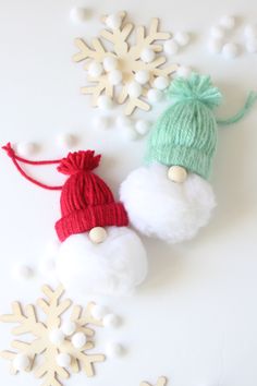 two snowflake ornaments are sitting on a white surface, one is green and the other is red