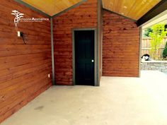 an empty room with wooden walls and a black door