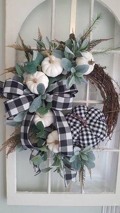 a wreath with white pumpkins and greenery