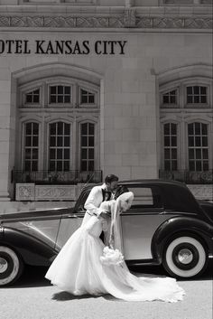 a bride and groom kissing in front of an old car outside the kansas city museum