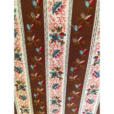 an ornately decorated brown and white ribbon with red, blue, green, and orange flowers