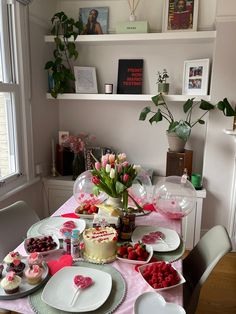 the table is set with cake, cupcakes and flowers