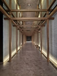 an empty hallway with wooden beams and white walls is lit by recessed light from the ceiling