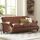 a brown leather couch sitting on top of a white rug