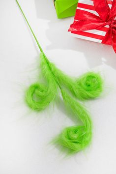 green hair is tied to a string with a red bow on it and two gift boxes in the background