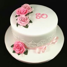 a white cake with pink flowers and the number 80 on it's side is shown