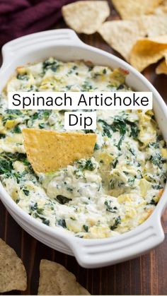 spinach dip with tortilla chips in a white casserole dish on a wooden table