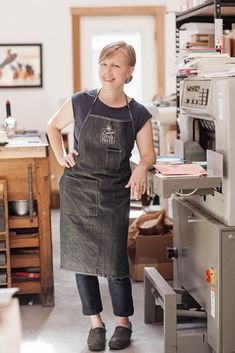 a woman wearing an apron standing next to a machine