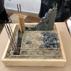 a construction project is being made with rocks and cement in a box on the table