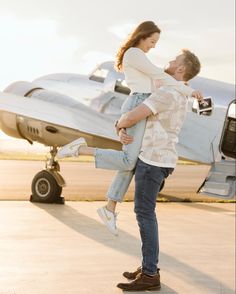 a man holding a woman in front of an airplane