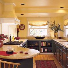 a kitchen with yellow walls and wooden flooring, an island countertop has wine glasses on it