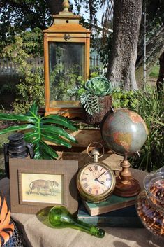 an assortment of antique items on a table with a mirror and other things around it