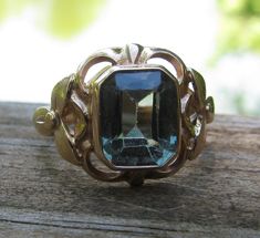 This is a really pretty antique ring. There are two little worn marks on the inside, it has been tested and is 14K gold. I brought the ring to my jeweler, and he looked at the stone under refractive light and identified it as synthetic spinel. Really pretty shade of green. This ring weighs 5.5 grams. The mount is really compelling with each side having a three petal ring in the mount. The face of the ring measures 3/4" across and 5/8" from top to bottom. This ring rests at a size 7.5 on a mandrel. Lovely! Petal Ring, Ring Flower, Antique Ring, Antique Rings, Vintage Costumes, Antique Art, Solitaire Ring, Shades Of Green, Women Rings