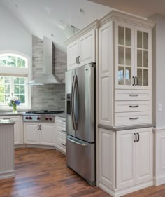 a large kitchen with white cabinets and stainless steel refrigerator freezer combo in the center