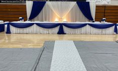 an empty dance floor with blue and white draping on the sides, along with tables set up for a banquet