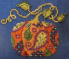 a cross stitched purse with beads on the front and side, sitting on a blue surface