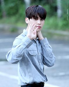 a young man standing in front of a parking lot holding his hands to his face