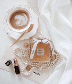 a bottle of chanel perfume sitting on top of a table next to a cup of coffee