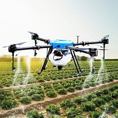 a large blue and white unmanned flying over a lush green field filled with lettuce