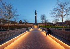 a person sitting on a bench in the middle of a walkway with lights around it