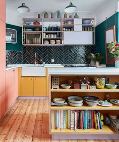 a kitchen with wooden floors and green walls, white cabinets and shelves filled with books