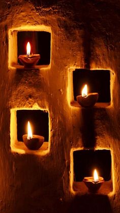 three lit candles sitting in the middle of a stone wall with small holes around them