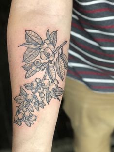 a woman's arm with an inked tattoo of berries and leaves on it