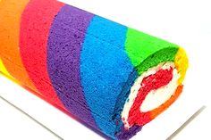 a roll of rainbow colored cake sitting on top of a white plate