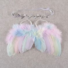 a pair of pastel colored feathers hang from a silver chain on a gray background